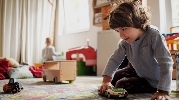Ein Junge spielt in einem Spielbereich mit einem Polizeiauto